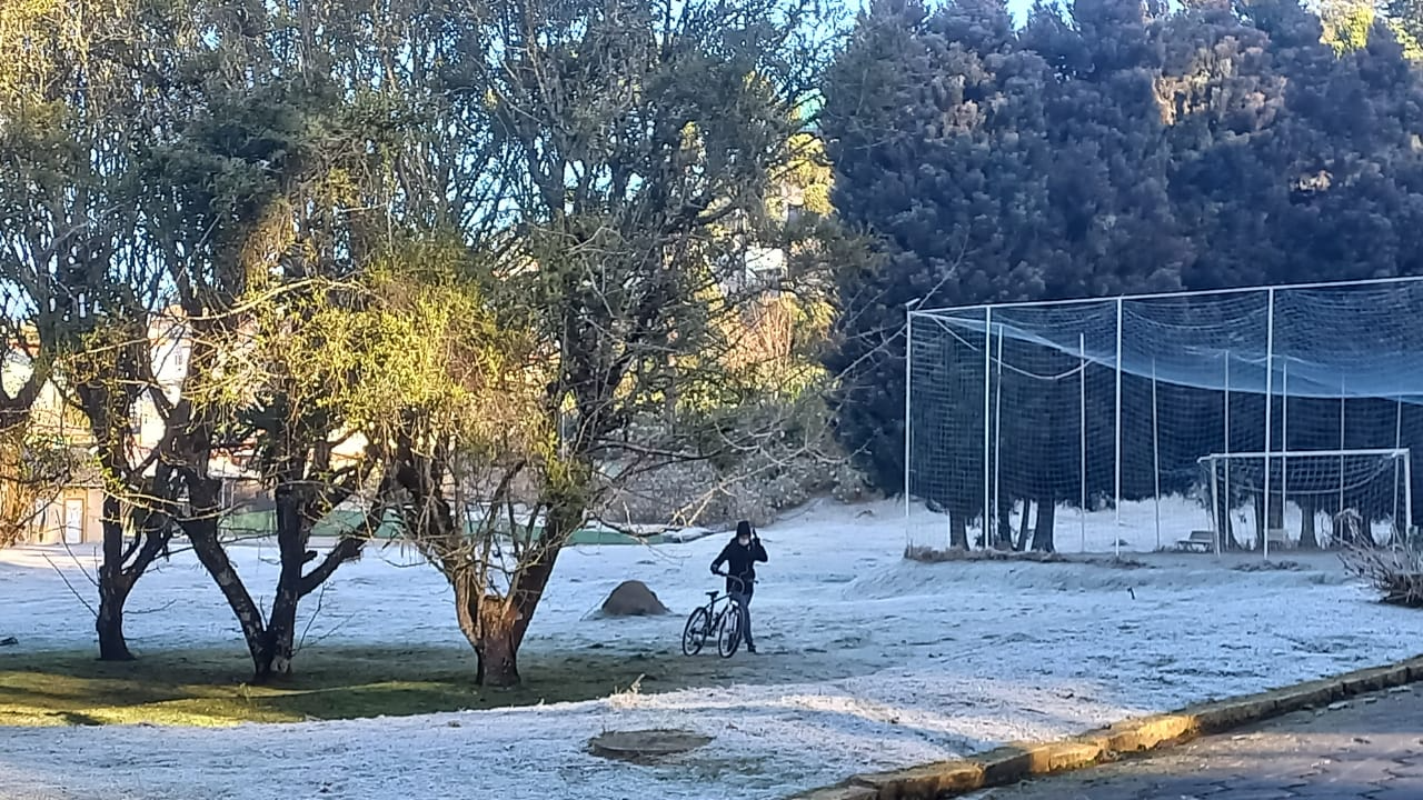 Ciclista passa com bicicleta em praça coberta por geada  Suzana Reis