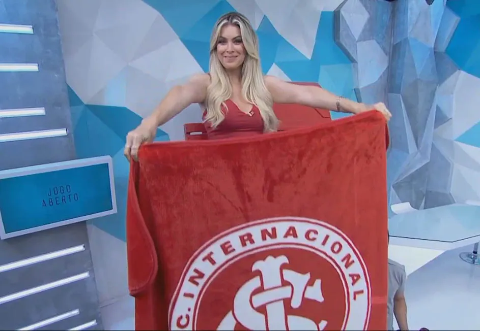 Renata Fan no topo da escada com a bandeira do Inter